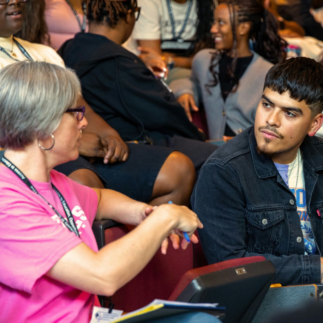A student listening as two people talk during a campus event