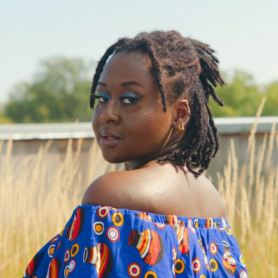 Portrait of a person in a colorful patterned top looking over their shoulder