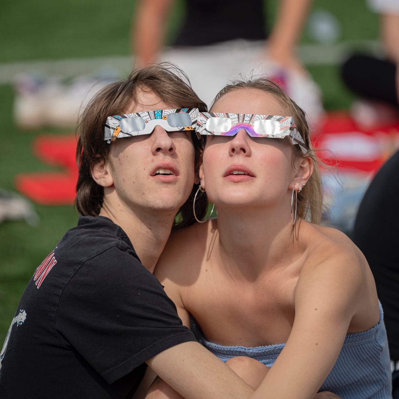 Two friends pressed cheek to cheek in eclipse glasses, April 2024